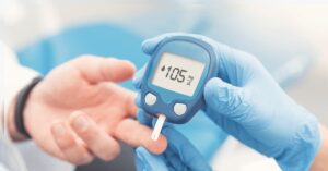Paciente con diabetes midiendo su nivel de glucosa en sangre con un glucómetro. Control glucémico y monitoreo de la diabetes con apoyo de nutrición especializada.