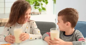 Niños sonrientes tomando un batido nutricional, ideal para apoyar la alimentación infantil con Nat100 Pediátrico.