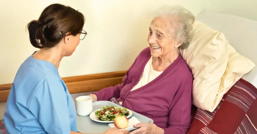 Cuidadora alimentando a una persona mayor con una comida saludable y rica en fibra, como apoyo nutricional y digestivo en adultos mayores en Chile.