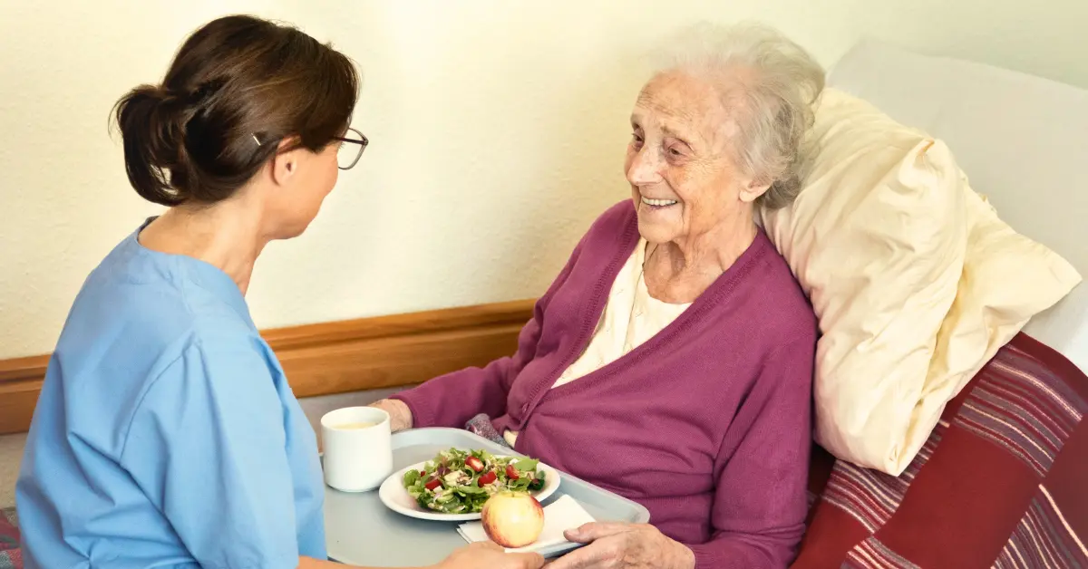 Cuidadora alimentando a una persona mayor con una comida saludable y rica en fibra, como apoyo nutricional y digestivo en adultos mayores en Chile.